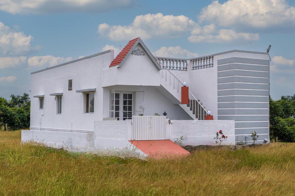 a white house with a staircase in a field at Maya Homez - Coimbatore in Coimbatore