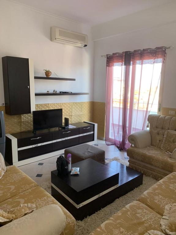 een woonkamer met een bank en een tv bij Ema Apartament in Durrës