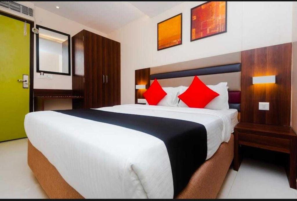 a bedroom with a large white bed with red pillows at Hotel Regal International - Near Mumbai International Airport Andheri East in Mumbai