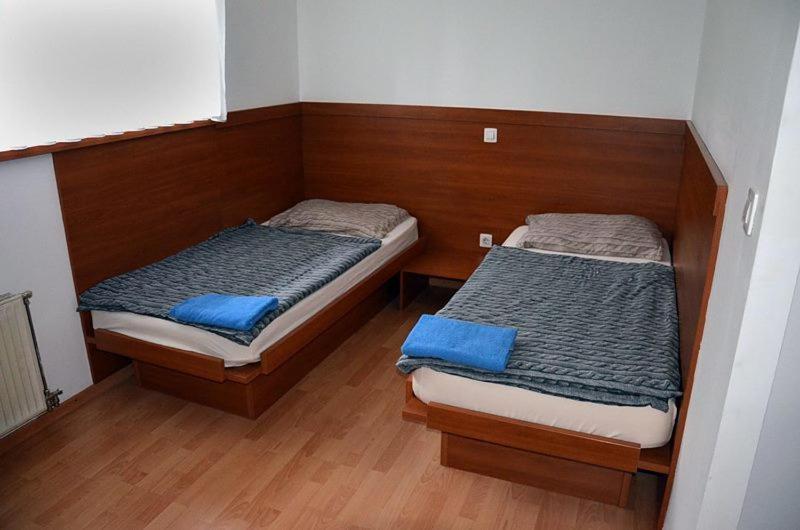 2 Betten in einem kleinen Zimmer mit Holzböden in der Unterkunft GOSTILNA IN PIZZERIA KOVAČ in Litija