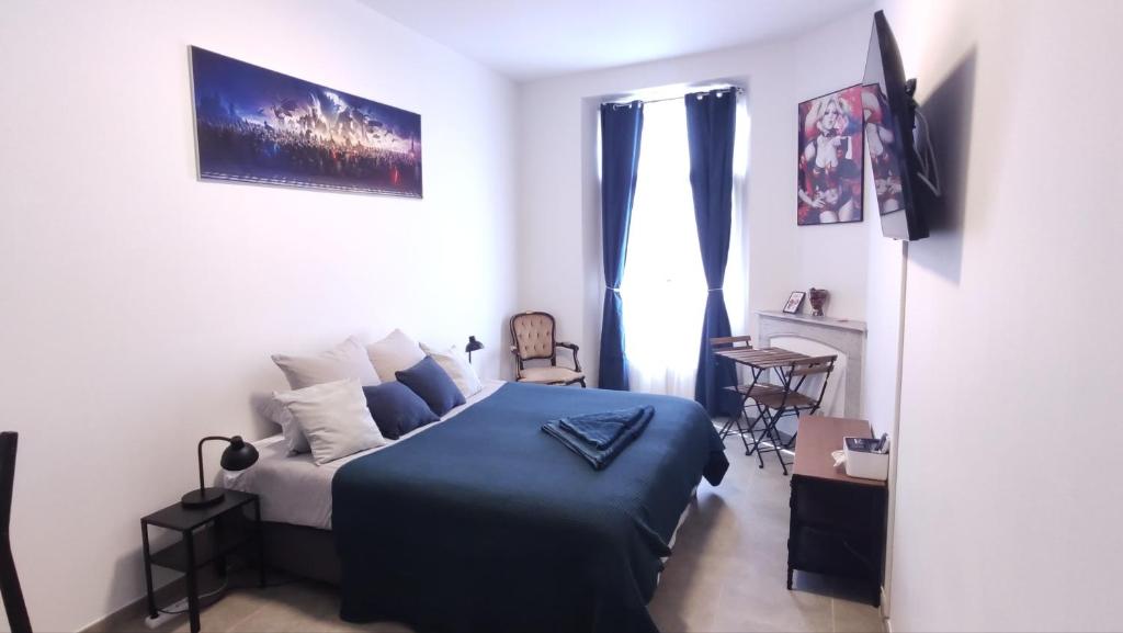 - une chambre avec un lit et une couverture bleue dans l'établissement Le QG, à Cannes