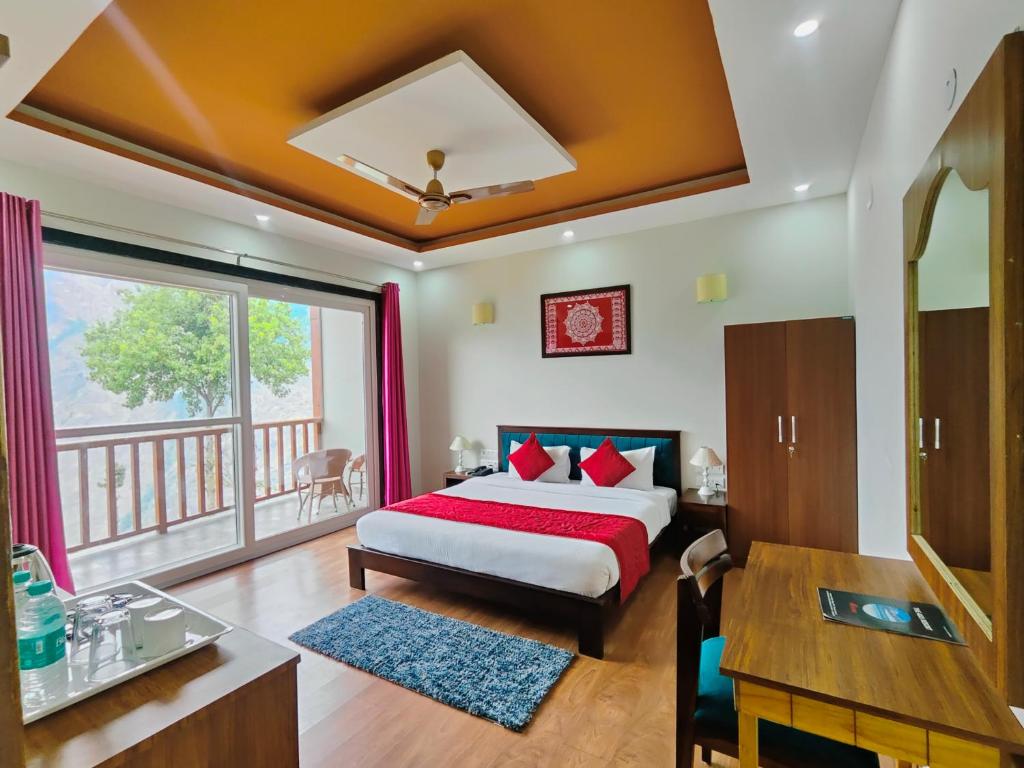 a bedroom with a bed and a desk and a window at Satopanth The Auli Resort By Royal Collection Hotels in Joshīmath