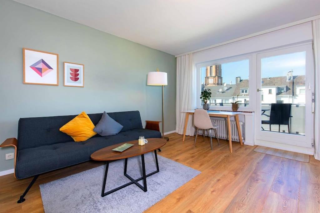 een woonkamer met een blauwe bank en een tafel bij City Apartment mit Sonnenbalkon in Wuppertal