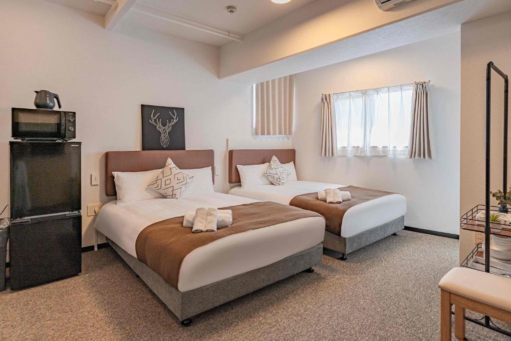 ein Hotelzimmer mit zwei Betten und einem Fernseher in der Unterkunft b&通天閣店 in Osaka