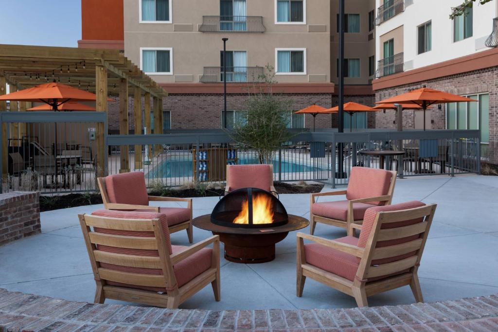 a fire pit with chairs and tables and umbrellas at Courtyard by Marriott Fort Worth Historic Stockyards in Fort Worth