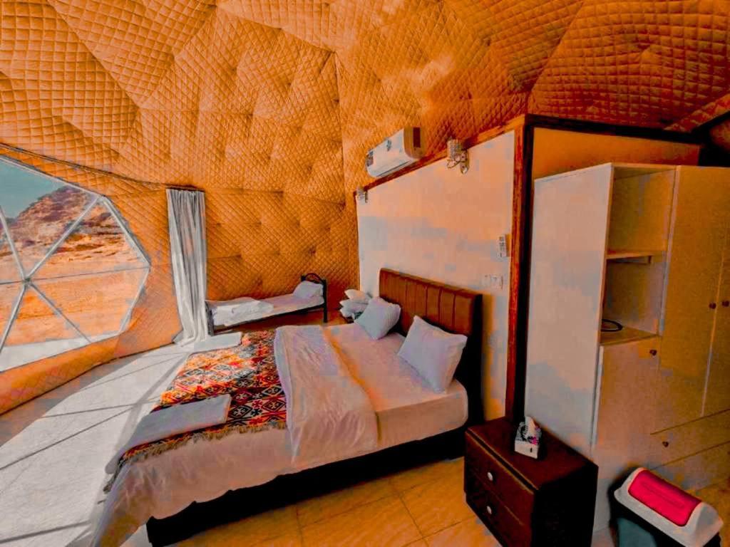 a bedroom with a bed and a large window at wadi rum camp stars & jeep tour in Wadi Rum
