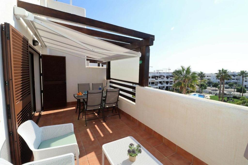 d'une terrasse avec une table et des chaises sur un balcon. dans l'établissement Nuestra Casa apartamento con terraza azotea y piscina compartida, à San Juan de los Terreros