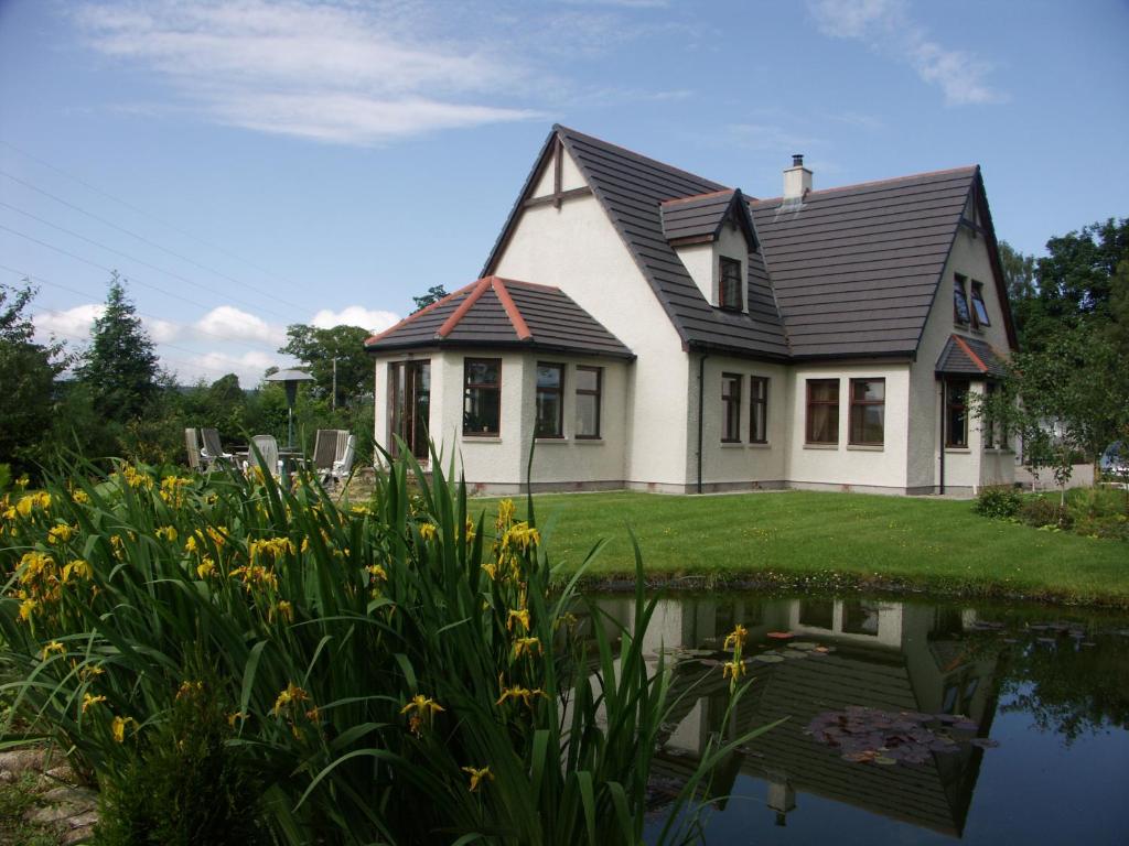 a house with a pond in front of it at Home Farm Bed and Breakfast in Muir of Ord