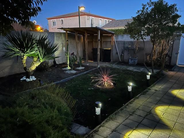 une maison avec une cour avec des plantes et des lumières dans l'établissement Maison au calme arborée, à Mauguio