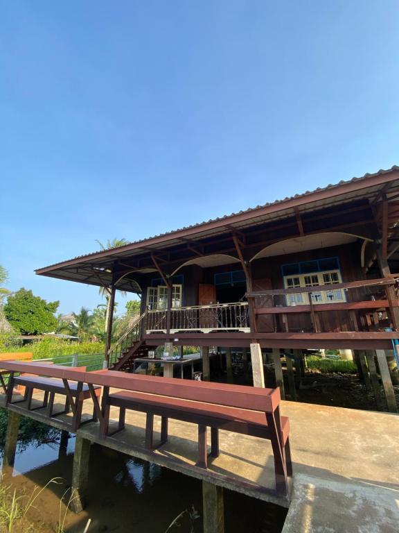ein Holzgebäude mit einer Bank im Wasser in der Unterkunft หนำเคียงคลอง ฟาร์มสเตย์ Kiangklong Farmstay in Ban Bang Pho