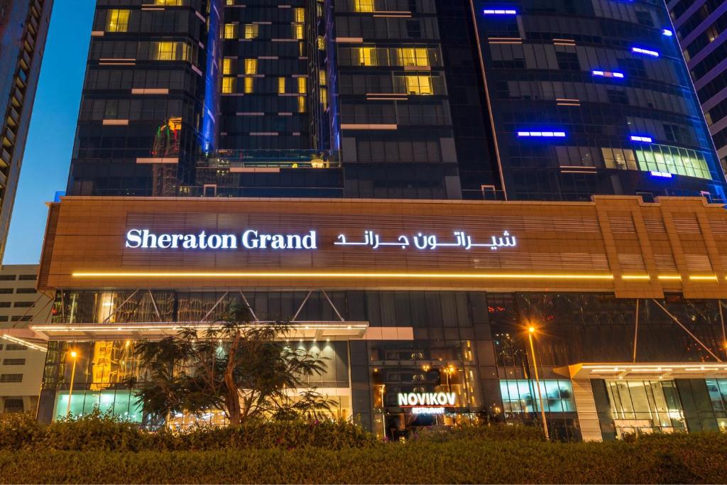 un grand bâtiment en forme la nuit avec des bâtiments dans l'établissement Sheraton Grand Hotel, Dubai, à Dubaï