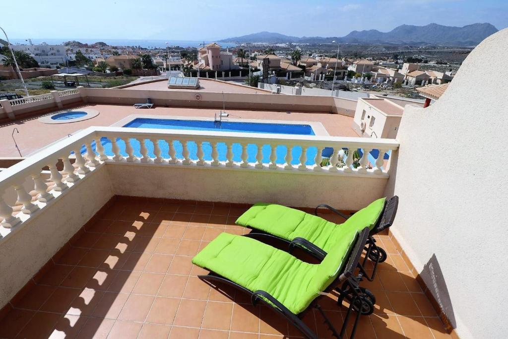 een groene stoel op een balkon met een zwembad bij El Cid apartamento soleado vista panorámica al mar y piscina comunitaria in San Juan de los Terreros