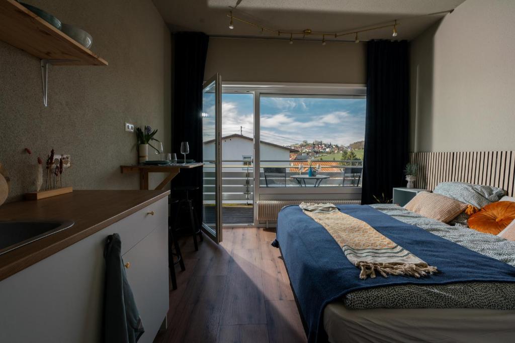 a bedroom with a bed and a kitchen with a window at Hotel Buchberg - Moderne Design-Apartments in Bermatingen