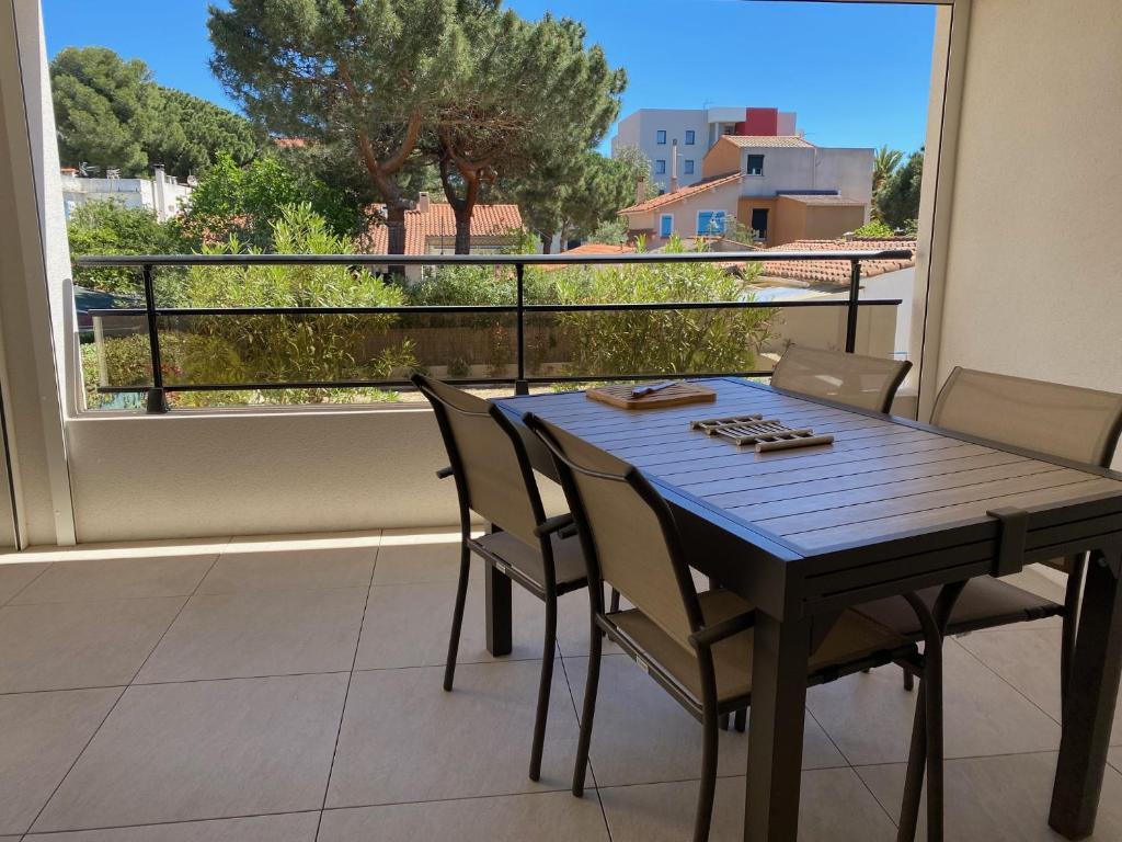 una mesa de madera y sillas en un balcón con vistas en Appartement neuf 4pers. 250 mètres de la plage, en Argelès-sur-Mer