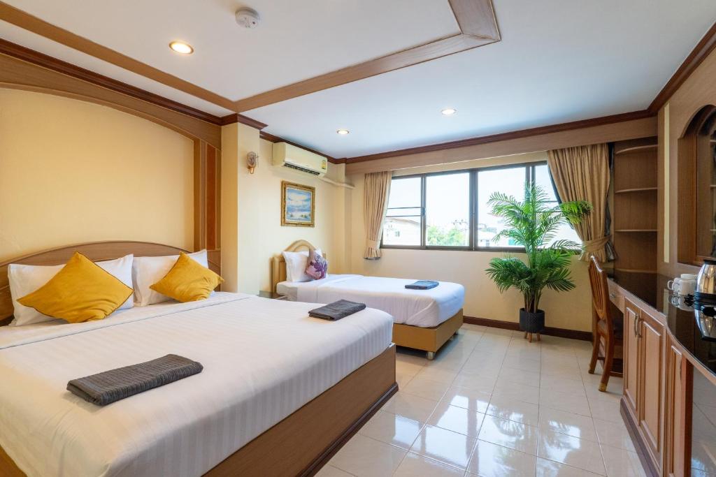 a hotel room with two beds and a window at La Casa South Pattaya Hotel in Pattaya South