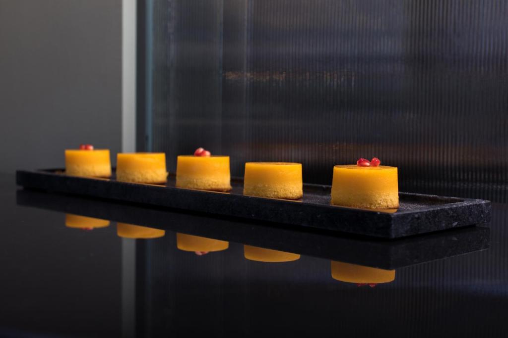 a row of yellow cakes on a black table at Brasil Suites Boutique Hotel in Athens