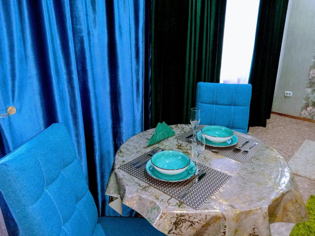 einen Tisch mit zwei blauen Tellern und Gläsern darauf in der Unterkunft Всегда рады гостям центр города in Oral