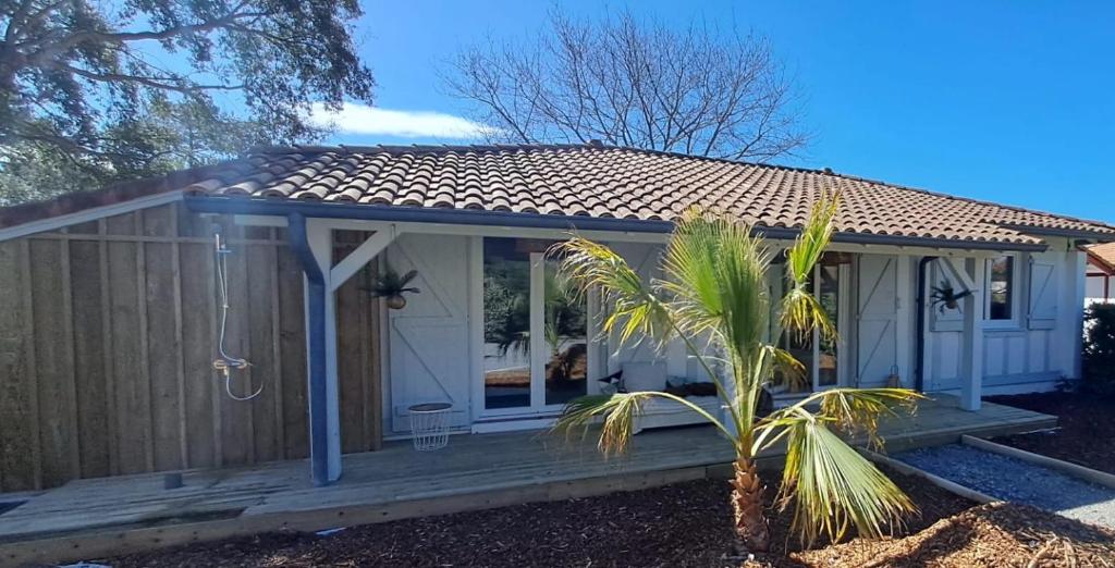 Ce petit cottage blanc dispose d'une terrasse couverte en bois. dans l'établissement villa VIEUX BOUCAU proche océan, à Vieux-Boucau-les-Bains