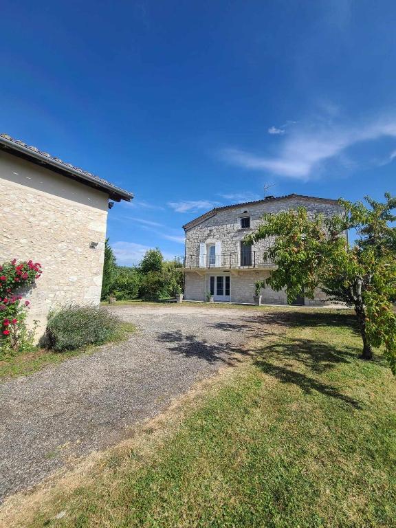 une grande maison en pierre avec un arbre en face de celle-ci dans l'établissement Naturaleza-Gîte les Cèdres, à Tournon-dʼAgenais