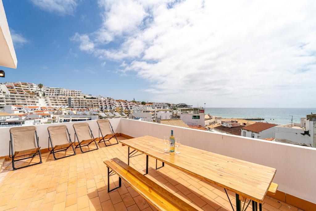 a wooden table on a balcony with a view of the ocean at Sandy Bottoms Hostel in Albufeira