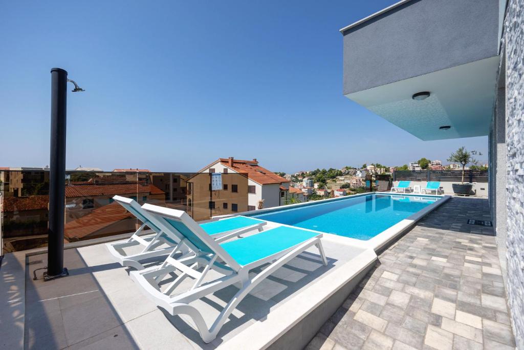 a pair of chairs and a swimming pool on a roof at Apartman Oliva and Studio Delux for a family with swiming pool, free parking, terace with view at the sea in Podstrana