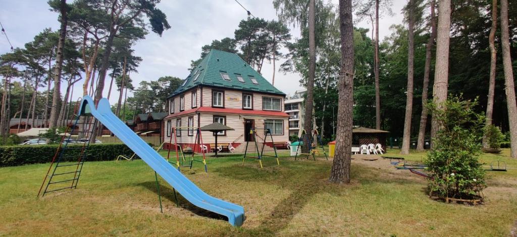 une aire de jeux en face d'une maison avec un toboggan bleu dans l'établissement Dom Wczasowy Bałtyk, à Ustronie Morskie