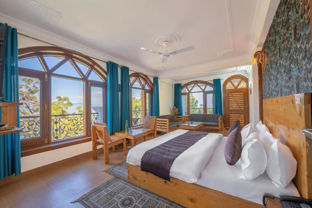 a bedroom with a large bed with blue walls and windows at Calm Cottage KASAULI HILLS Barog in Barog