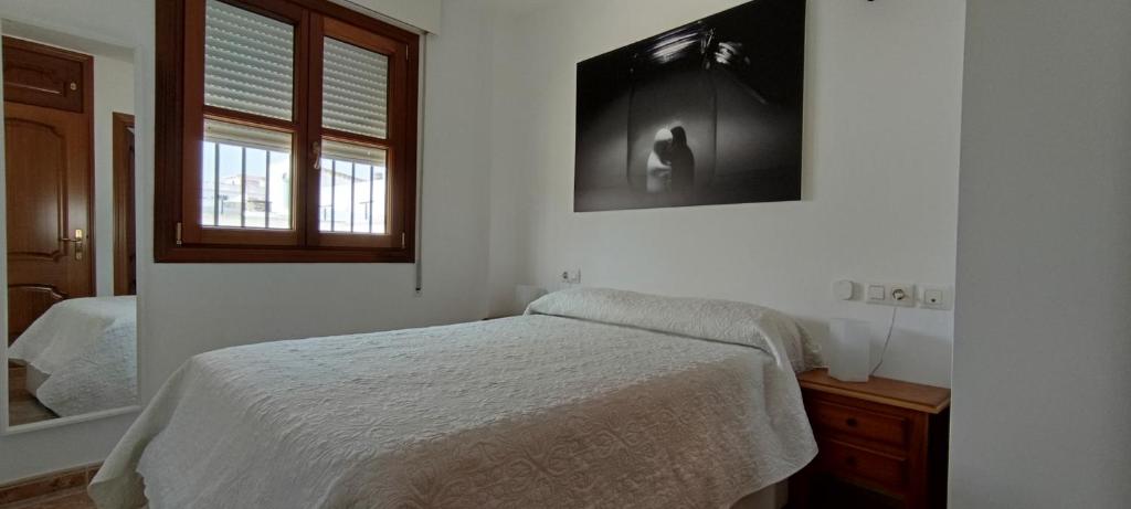 een witte slaapkamer met een bed en een raam bij Apartamento atico Terraza Centro in El Puerto de Santa María