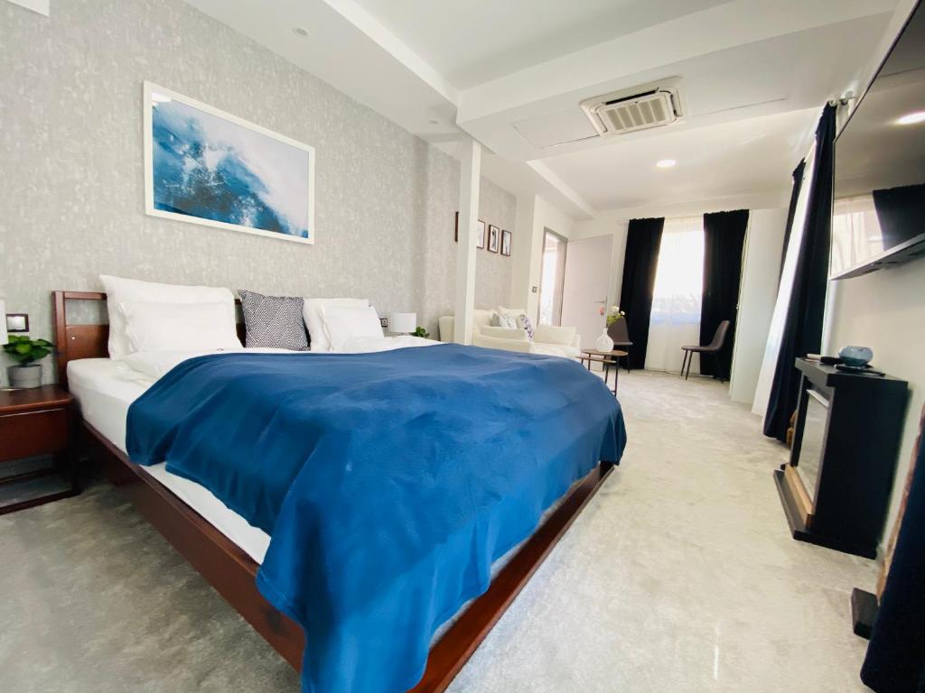 1 dormitorio con 1 cama grande con manta azul en Hotel Dolce Vita, en Balatonkenese