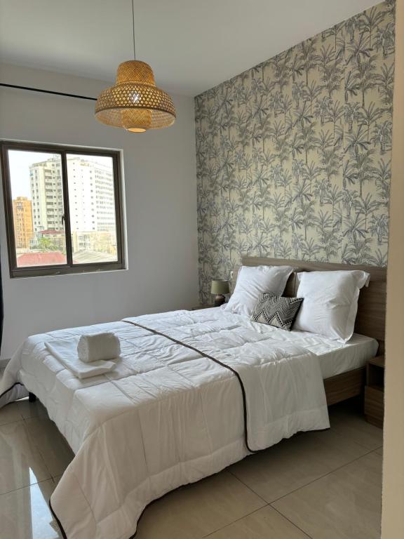 ein Schlafzimmer mit einem großen weißen Bett mit einer Wand in der Unterkunft HAYDEN HOME in Libreville