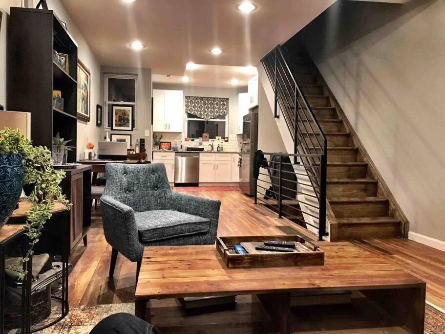 uma sala de estar com um sofá, uma mesa e uma escada em Modern South Philly Townhome em Filadélfia