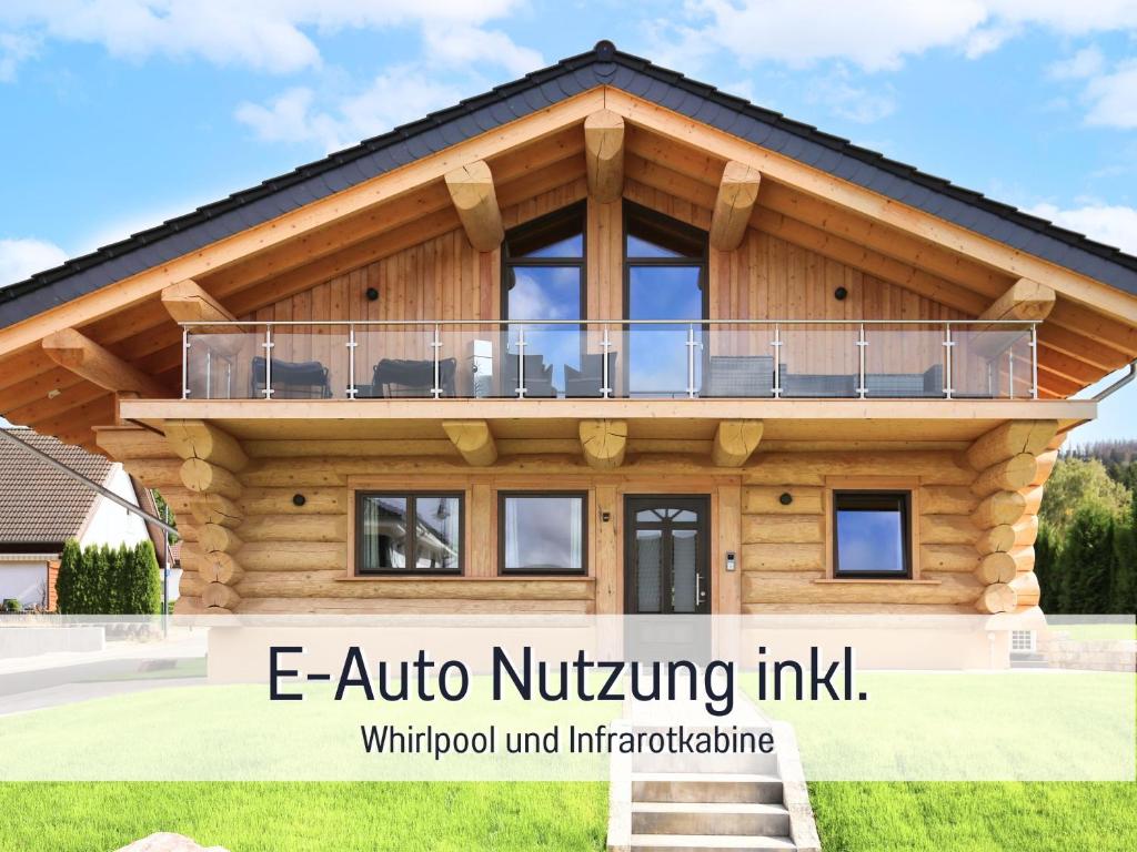 une maison en rondins avec une terrasse couverte et les mots e auto nir sauting dans l'établissement Natur-Chalet zum Nationalpark Marie-Luise inkl E-Auto, à Allenbach