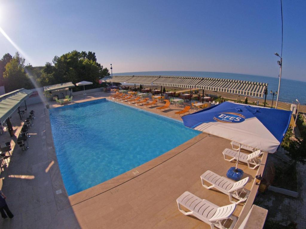 a swimming pool with chairs and umbrellas next to the ocean at Mora Hotel in Trabzon