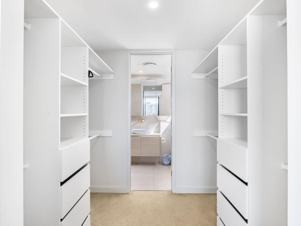 a white walk in closet with white shelves at Sweeping Ocean view Apt w Carpark and rooftop pool in Gold Coast