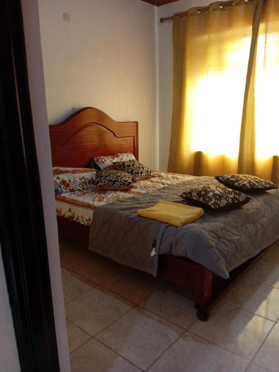 a bedroom with a bed with a wooden headboard and a window at NEW VILLA TWO ROOMS KANOMBE in Kigali