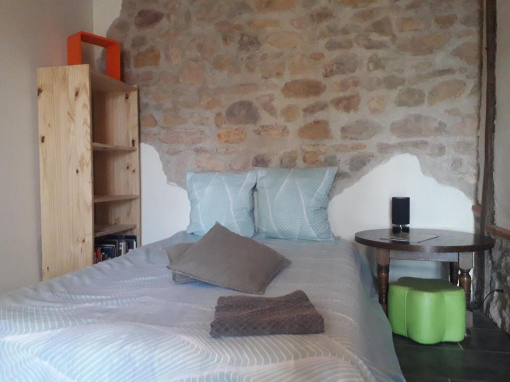 a bedroom with a bed with a stone wall at Chambre double in Vallon-en-Sully