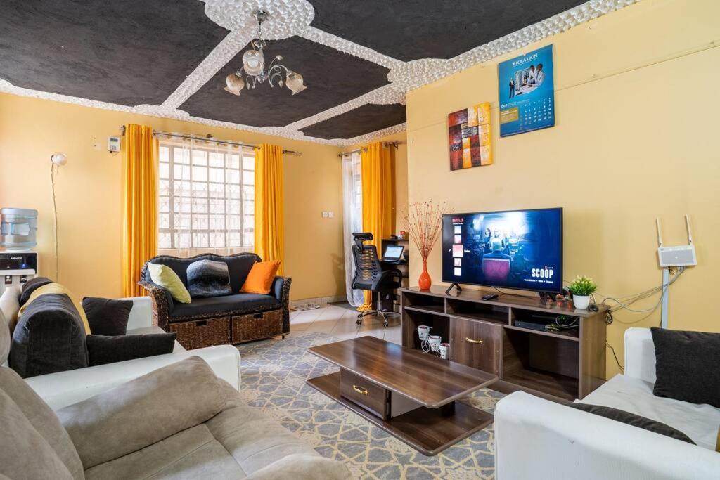 a living room with couches and a flat screen tv at Spacious 2-BR Apartment In Membley in Ruiru