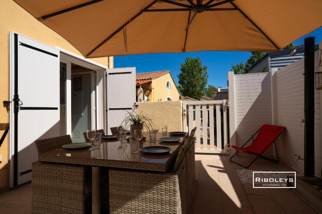 - une table en bois avec un parasol sur la terrasse dans l'établissement Maison rénovée et climatisée avec WIFI à 600m de la plage, à Vias