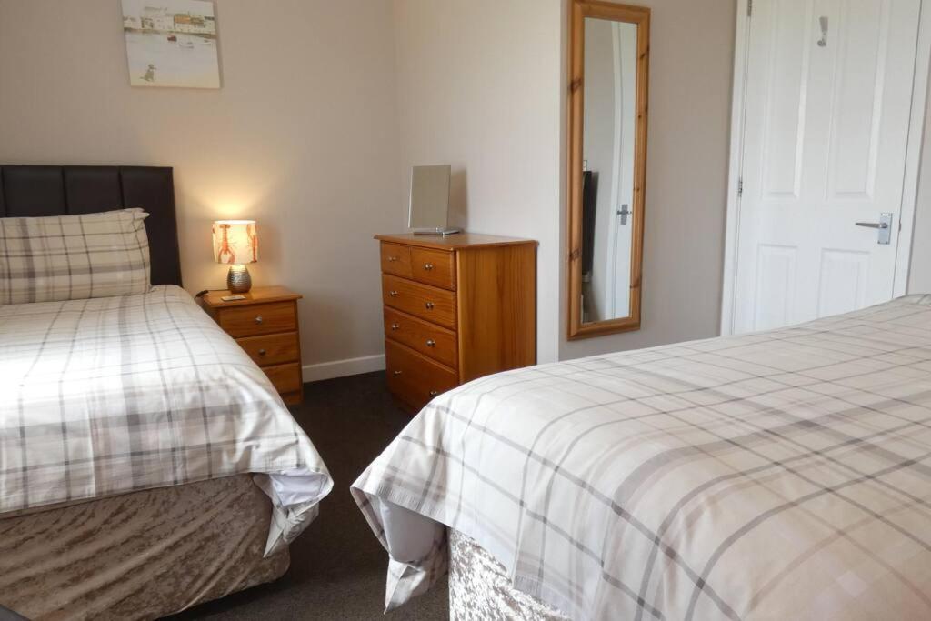 una camera con due letti e un comò con specchio di Two Bedroomed Holiday Cottage with Sea Views a St Austell