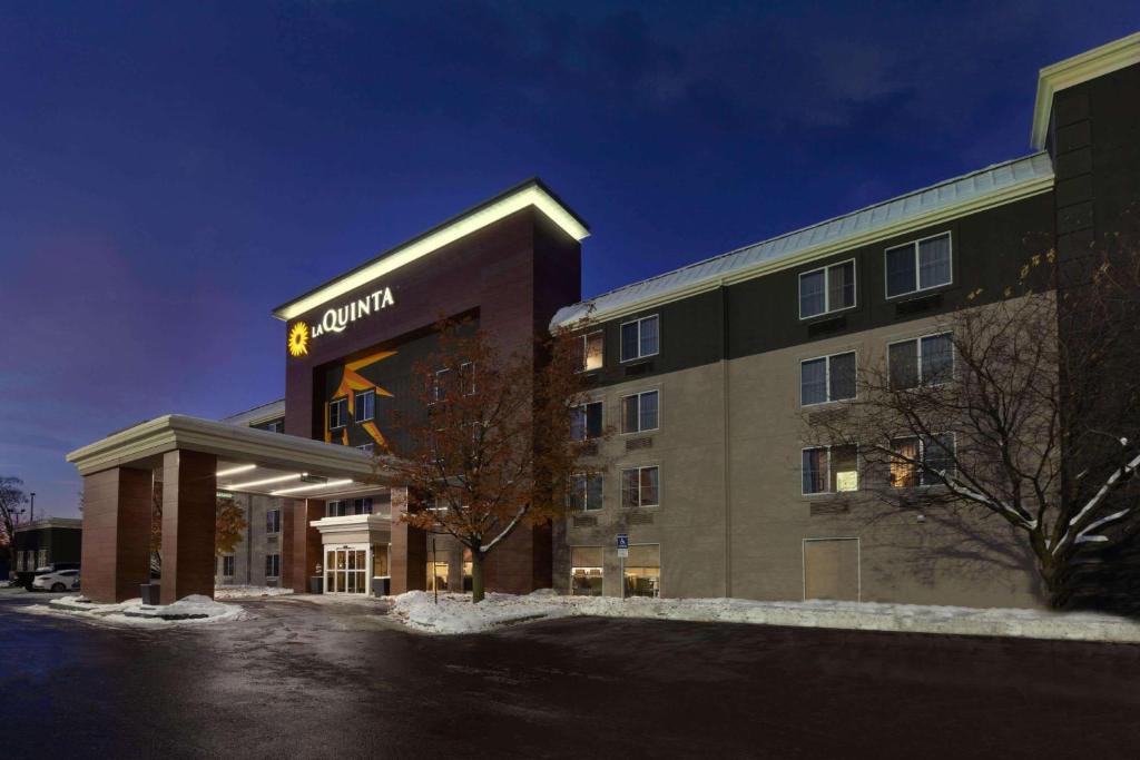 a hotel building with a sign on the front of it at La Quinta by Wyndham Detroit Utica in Utica
