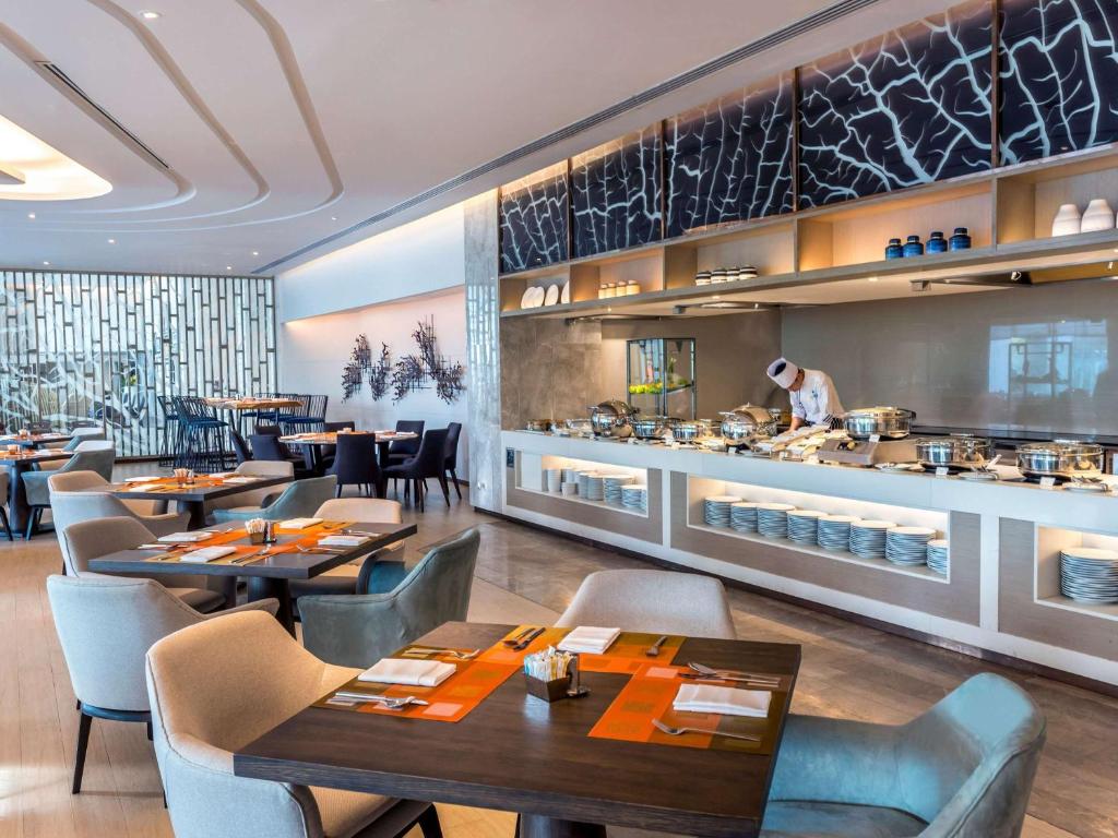 a restaurant with tables and chairs and a chef preparing food at Novotel Phuket City Phokeethra in Phuket Town