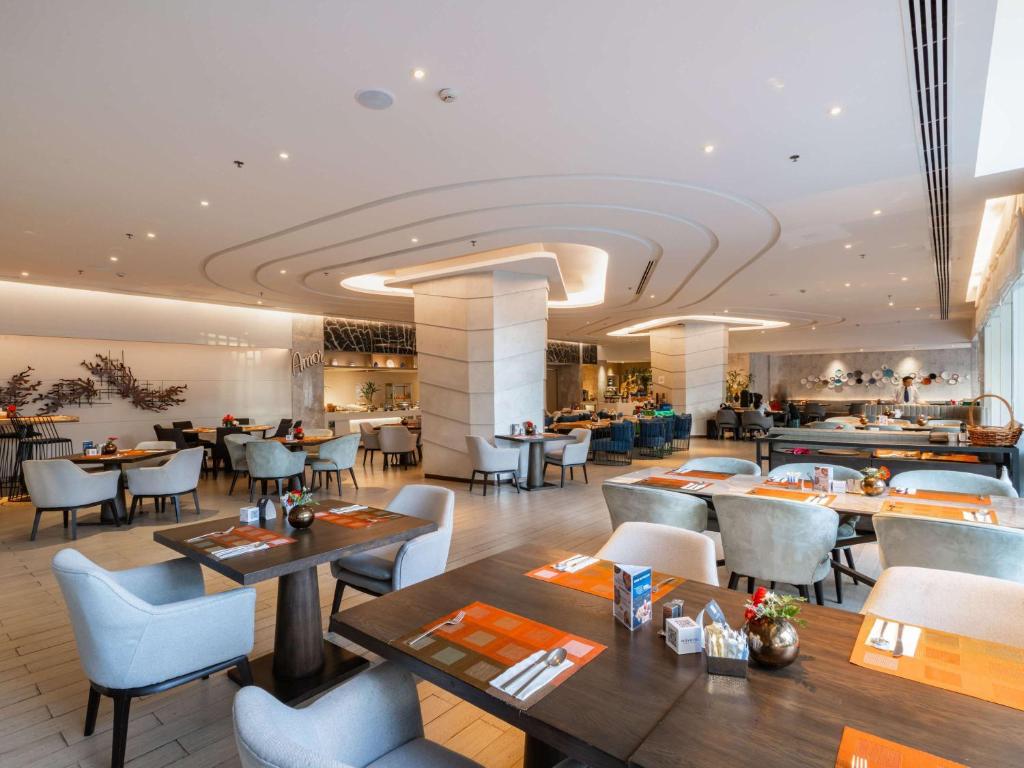 a dining room with tables and chairs and a restaurant at Novotel Phuket City Phokeethra in Phuket Town