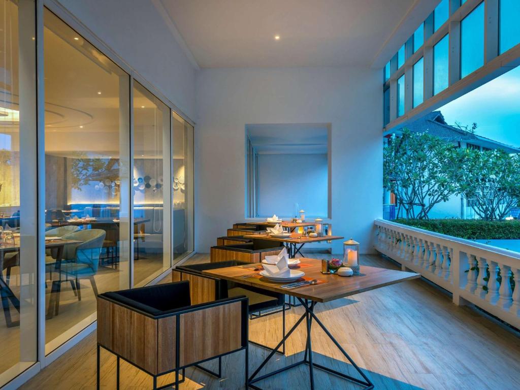 a restaurant with tables and chairs in a room at Novotel Phuket City Phokeethra in Phuket Town