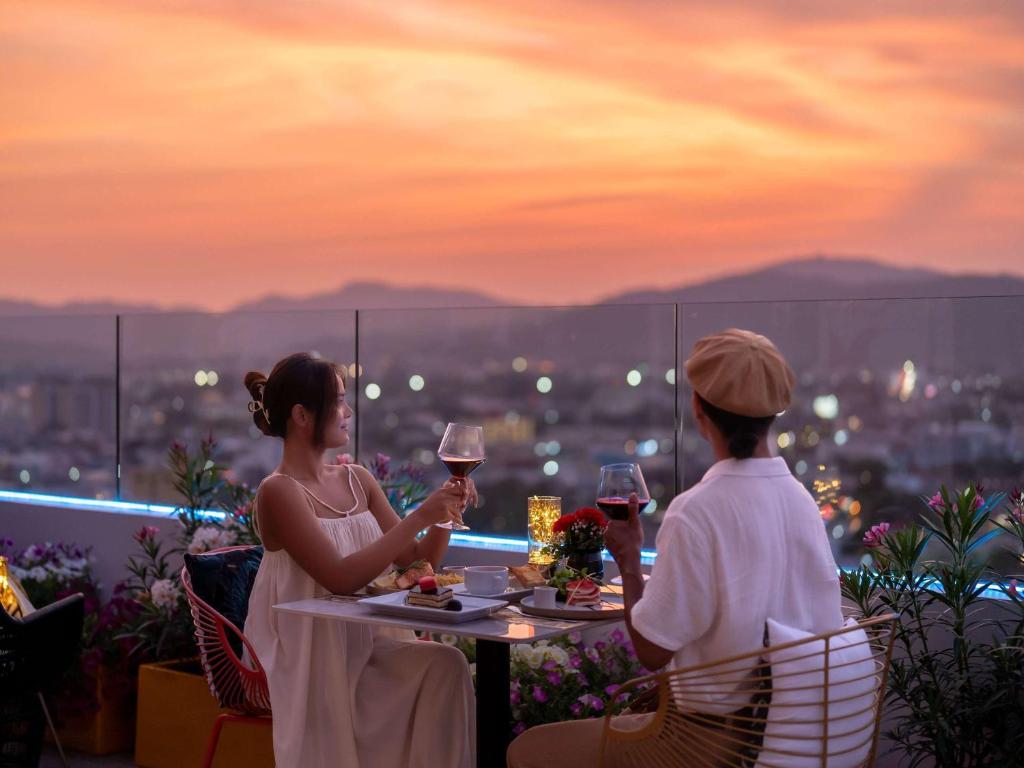 two women sitting at a table with wine glasses at Novotel Phuket City Phokeethra in Phuket Town