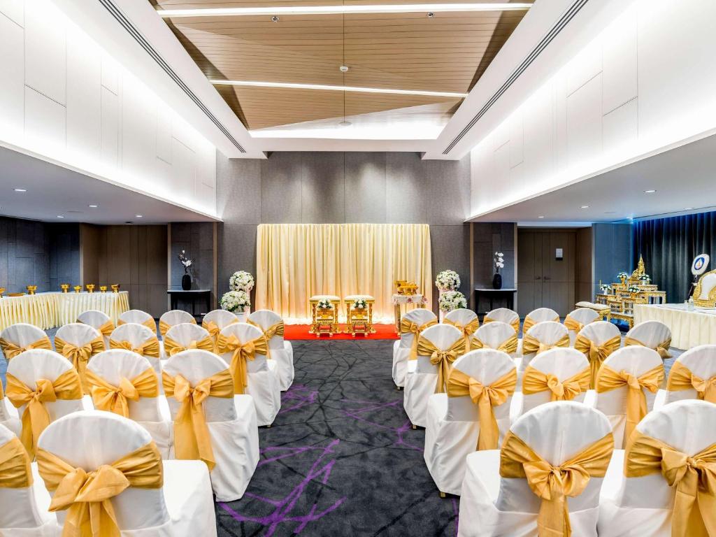 a banquet hall with white chairs and tables with bows at Novotel Phuket City Phokeethra in Phuket Town