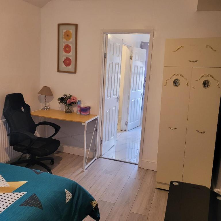 a bedroom with a desk and a table and a chair at Greenwich City Staycation in Plumstead