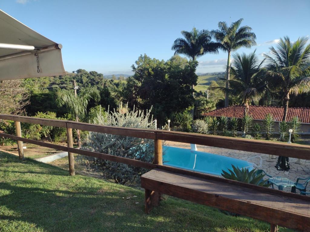 a wooden bench sitting in the grass next to a pool at Chácara pedacinho do céu in Socorro