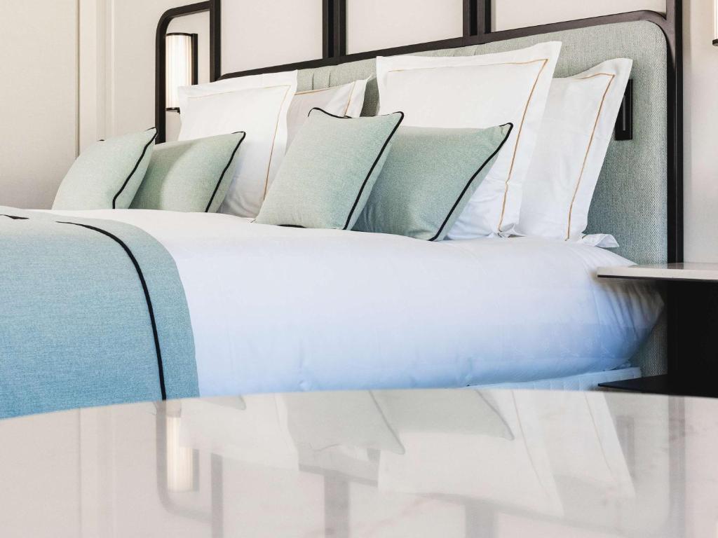 a bed with white and blue pillows on it at Mondrian Cannes in Cannes