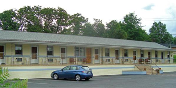 une voiture bleue garée devant un bâtiment dans l'établissement Budget Host Inn, à New Berlinville
