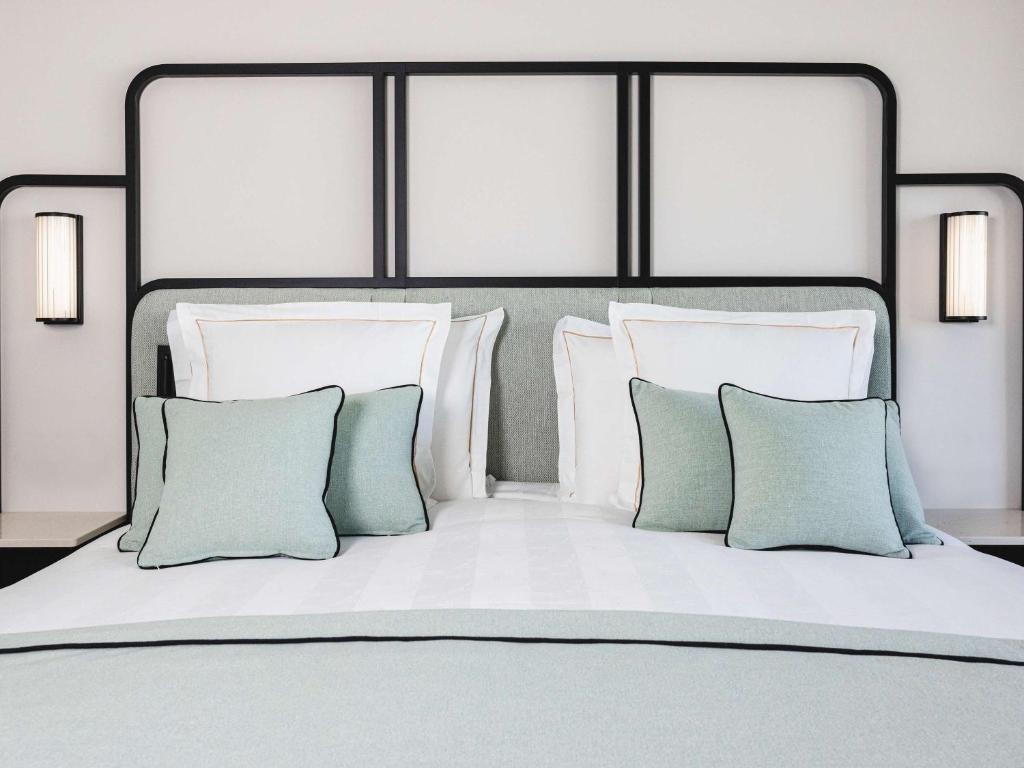 a bed with white and green pillows on it at Mondrian Cannes in Cannes